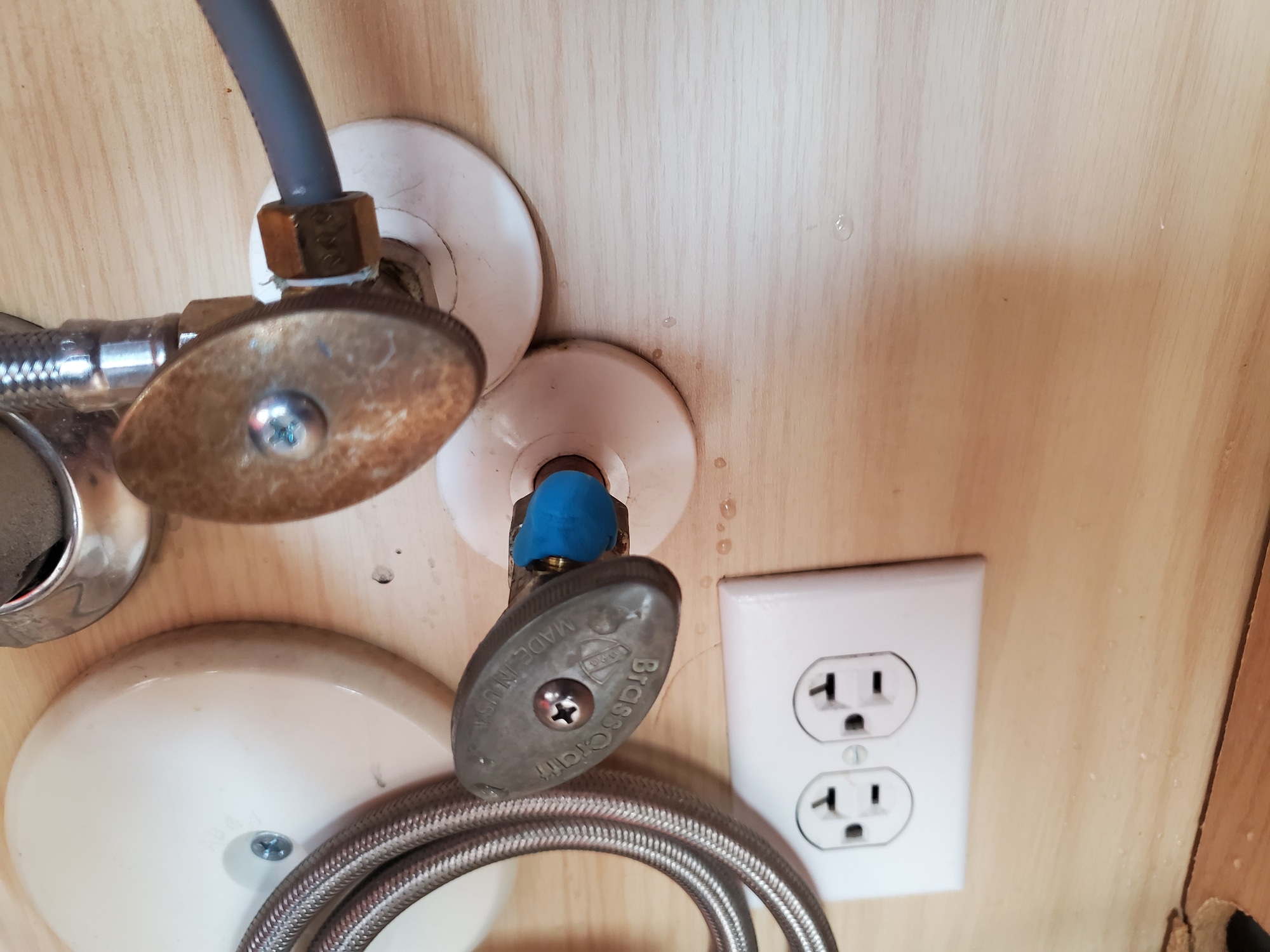 Angle stop valves under the kitchen sink by the outlet.